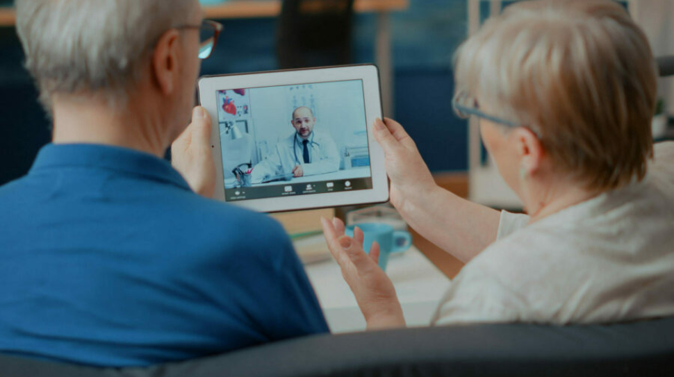 Senior couple attending online meeting with doctor on digital tablet, doing remote consultation at home. Elder people using videoconference call on modern gadget for internet telemedicine.